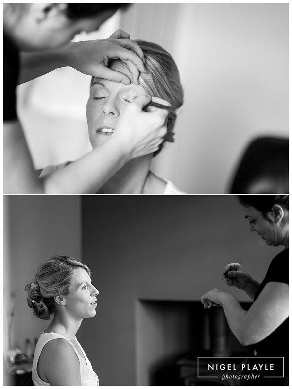 A bride is getting her makeup done by a wedding photographer.
