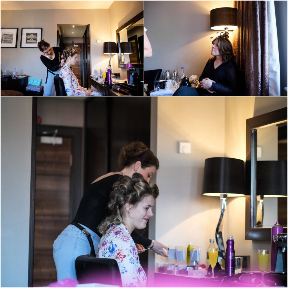 A woman is getting her hair done in a hotel room for her wedding.