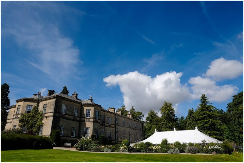A white tent in front of a large mansion, perfect for an elegant wedding photography session.