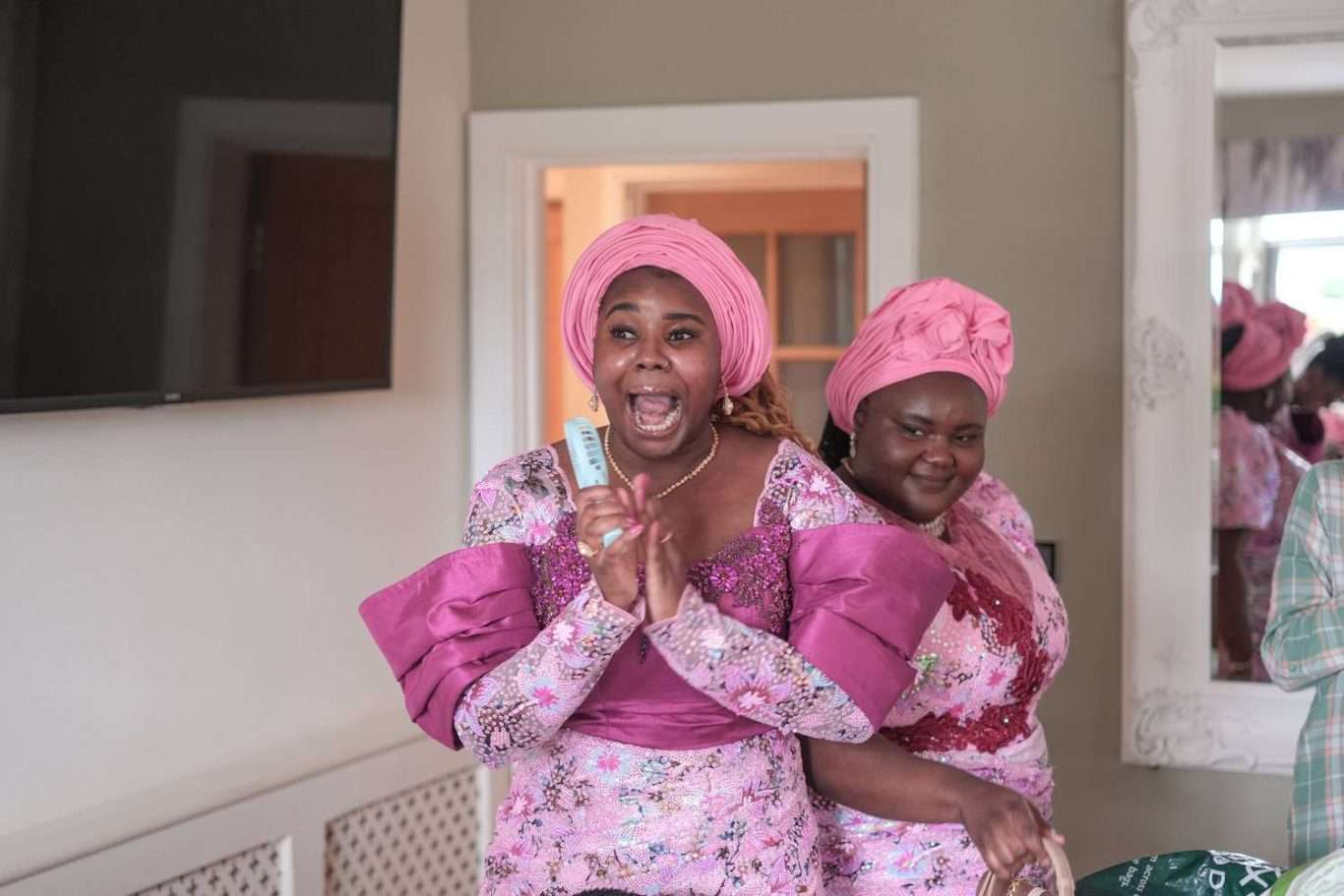 A group of women dressed in pink turbans are standing in front of a mirror.