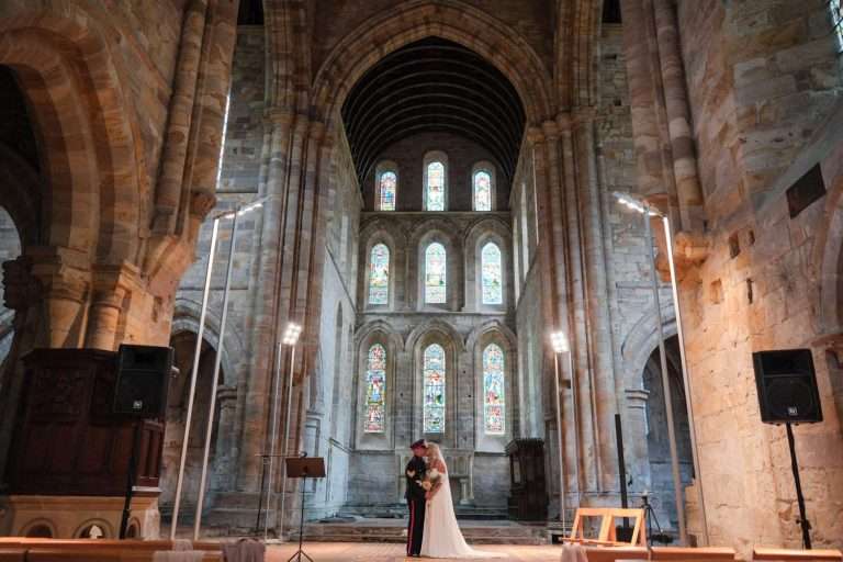 A bride and groom standing in the middle of Brinkburn Priory.